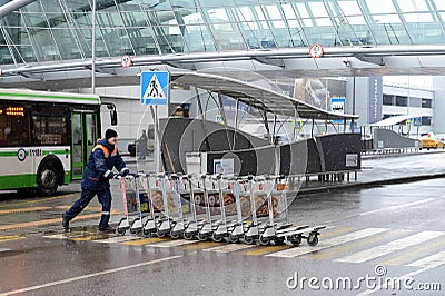 A worker pushes Luggage carts at Moscow`s Sheremetyevo international airport Editorial Stock Photo