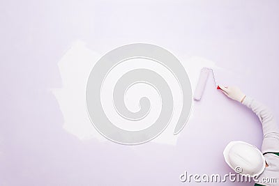 A worker puts paint on a white spot on a purple wall Stock Photo