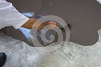 Worker puts a self leveling screed on cement floor. Stock Photo