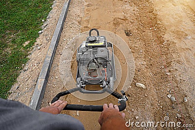 Worker rams the ground with a vibrating machine. Top view Stock Photo