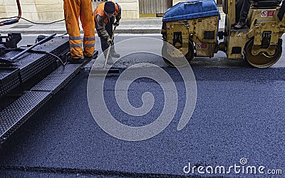 Worker regulate tracked paver laying asphalt Stock Photo