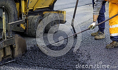 Worker regulate tracked paver laying asphalt Stock Photo