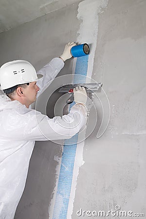 a worker reinforces the cracked wall with mesh Stock Photo