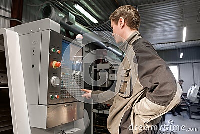 Worker removes the part from CNC lathe machine. Turning machine for drilling with the drill tool and center drill tool .The hi- Editorial Stock Photo