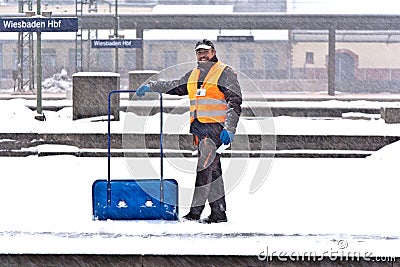 Worker removing snow from the station platform Editorial Stock Photo