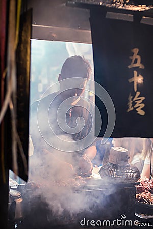 Worker of the restaurant preparing the food for the customer at traditional bar in Omoide Yokocho, Shinjuku. Portrait Orientation Editorial Stock Photo