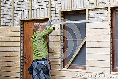 Worker restoring old brick house facade with new wooden planks Stock Photo
