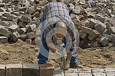 Worker: road builder laying cobblestones Editorial Stock Photo
