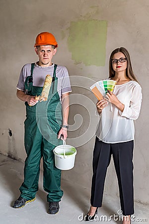 Worker with roller and paint bucket and woman with colour sampler Stock Photo