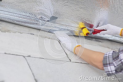 A worker rolls a vapor barrier joint with a roller Stock Photo