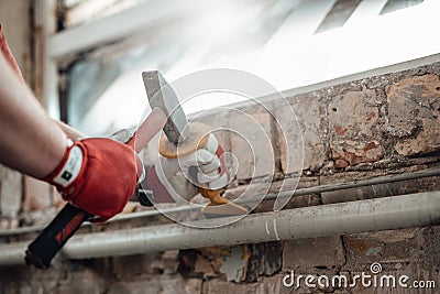 Builder`s strong hands working with hammer and chisel at the construction site Stock Photo