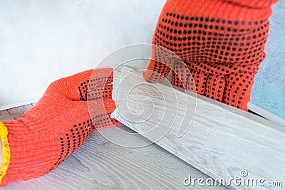 Worker`s hands Instal plastic skirting board and decorative caps. Renovation of baseboard at home Stock Photo