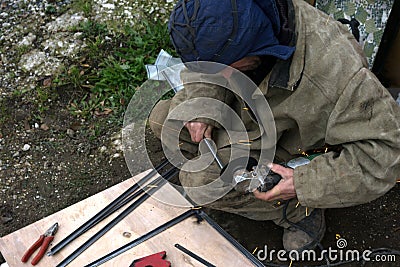 Worker sawing metal with electrical saw, grinder. Editorial Stock Photo