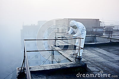 Worker scientist wearing protective coverall and gas mask doing ecological tests on the roof Stock Photo