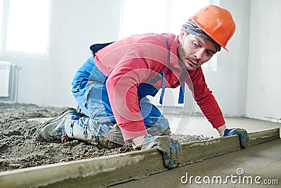 Worker screeding indoor cement floor with screed Stock Photo