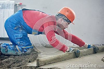 Worker screeding indoor cement floor with screed Stock Photo