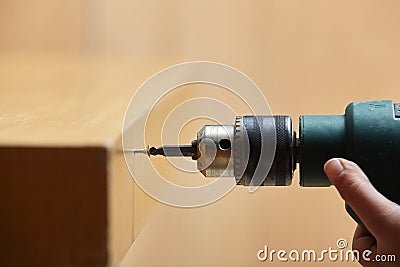 Worker screwing a into a wooden table with an electric scr Stock Photo
