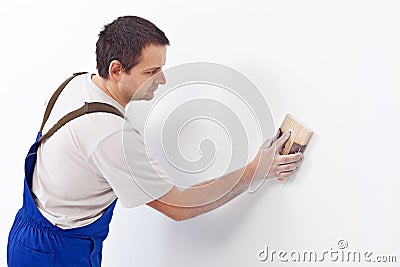 Worker scrubbing the wall with sandpaper Stock Photo