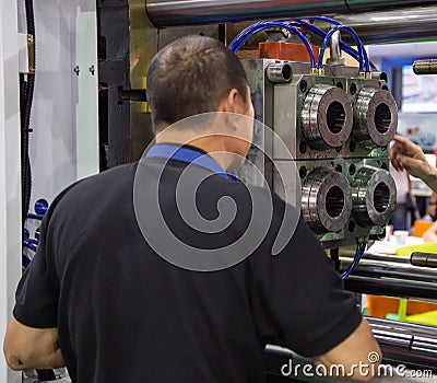 Worker operate injection molding press machine Editorial Stock Photo