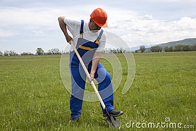 Worker with Shovel on a Green Lawn Stock Photo