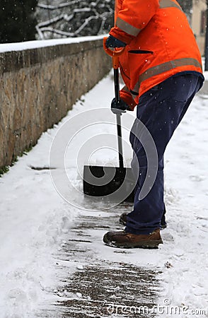 Worker while shoveling snow from frozen sidewalk Stock Photo