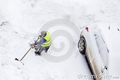 Worker shoveling snow near cars on parking. Top view Editorial Stock Photo