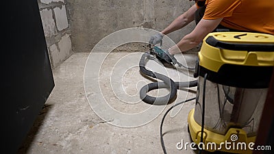 A worker smoothest the floor with an angle grinder. Grinding a concrete floor with a grinding machine before repair. A Stock Photo