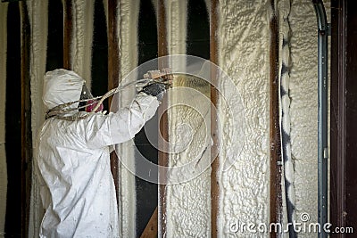 Worker spraying closed cell spray foam insulation on a home wall Stock Photo