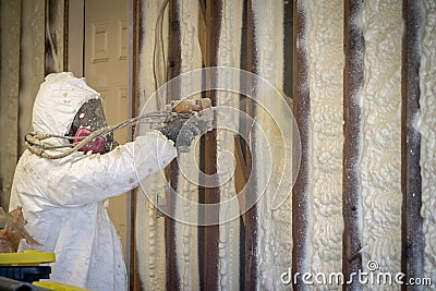 Worker spraying closed cell spray foam insulation on a home wall Stock Photo