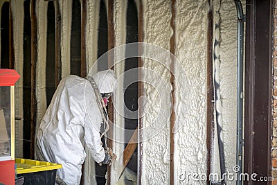 Worker spraying closed cell spray foam insulation on a home wall Stock Photo