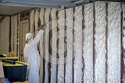 Worker spraying closed cell spray foam insulation on a home wall Stock Photo