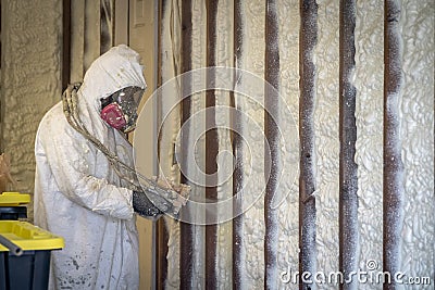 Worker spraying closed cell spray foam insulation on a home wall Stock Photo