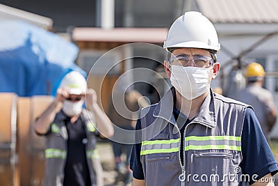 The worker staff, engineer protects himself from covid-19 coronavirus with a protective mask in the construction site. Stock Photo