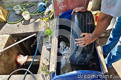 Worker submerge tyre into water container for bubble to check point of punctured Stock Photo