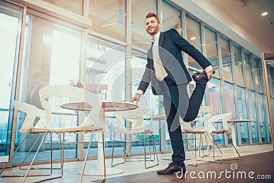 Worker stretching leg at table in office. Stock Photo