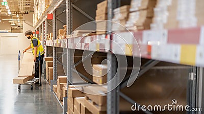 The worker taking package from the shelf put on a push cart at the large warehouse Editorial Stock Photo