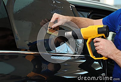 Worker tinting car window with heat gun in workshop, closeup Stock Photo