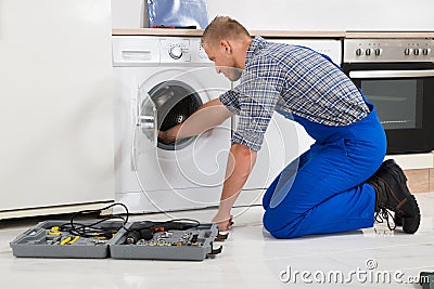 Worker With Toolbox Repairing Washing Machine Stock Photo