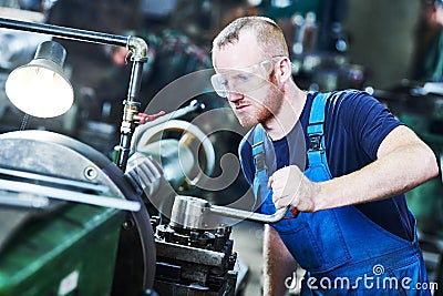 Worker turner operating lathe machine at industrial manufacturing factory Stock Photo