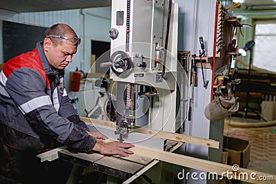 The worker cuts a bar on a jigsaw machine Stock Photo