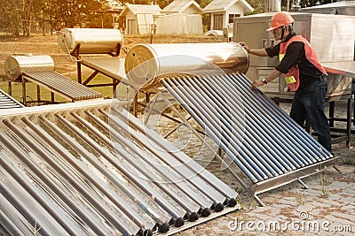 The worker in uniform and helmet checks concentrating Solar Power with Flat Plat collector and Evacuum Tube Collector. Stock Photo