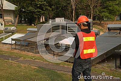 The worker in uniform and helmet checks concentrating Solar Power with Flat Plat collector and Evacuum Tube Collector. Stock Photo