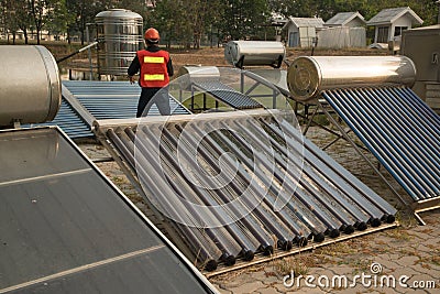 The worker in uniform and helmet checks concentrating Solar Power with Flat Plat collector and Evacuum Tube Collector. Stock Photo