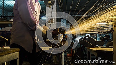 Worker uses grinding cut metal, focus on flash light line of sharp spark,in low light Stock Photo