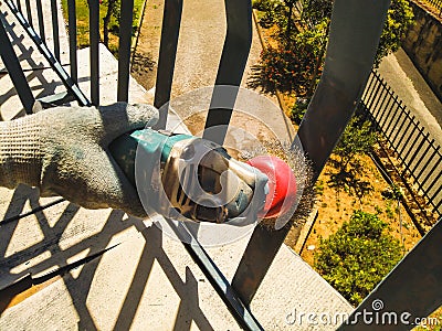 The worker uses a sander to clean the railing from paint Stock Photo