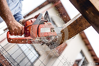 Worker using chainsaw for cutting timber wood, construction material, trimming and slicing logs Stock Photo