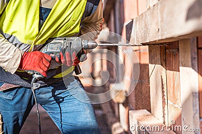 Worker using a drilling power tool on construction site Stock Photo