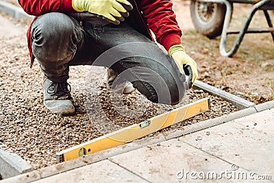 Worker using pavement slabs and level to build stone sidewalk. Close up of construction worker installing and laying pavement ston Stock Photo