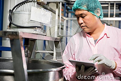 Worker using tablet in beverage factory oversees soda water filling Stock Photo
