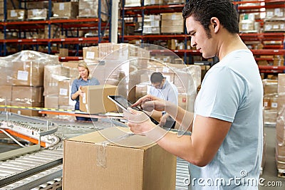 Worker Using Tablet Computer In Distribution Warehouse Stock Photo